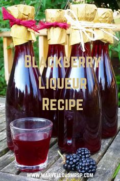 three bottles of blackberry liqueur next to a glass of blackberries