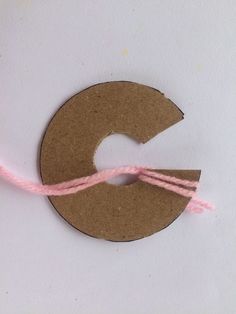 a piece of brown paper with pink string on it and a circle cut out of cardboard