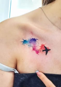 a woman's shoulder with an airplane tattoo on her left shoulder and the plane painted in watercolors