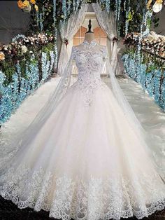 a white wedding dress on display in front of flowers