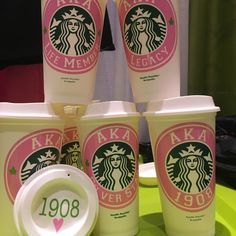 starbucks coffee cups with pink and white designs on them are sitting on a green tray