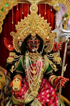 an idol is displayed in front of a red curtain