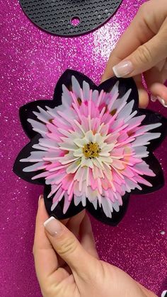 someone is holding a pink and white flower in their left hand on a purple background