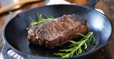 a steak is cooking in a skillet on the table