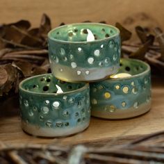 three tealight candles sitting on top of each other in front of some dry leaves