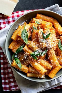 a bowl filled with pasta and parmesan cheese on top of a checkered table cloth