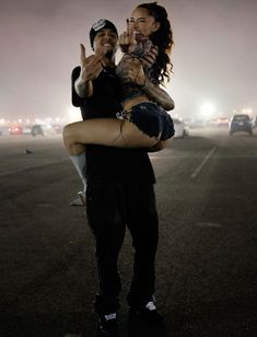 a man carrying a woman on his back in the middle of a parking lot at night