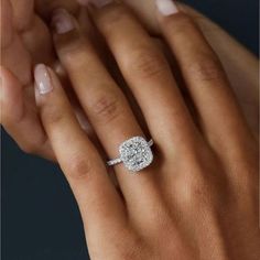 a woman's hand holding an engagement ring in her left hand, with the center diamond