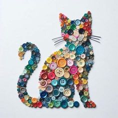 a cat made out of buttons sitting on top of a white table next to a wall