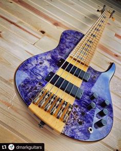 a blue and yellow bass guitar sitting on top of a wooden floor next to a wall