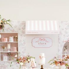 a table topped with lots of cakes and cupcakes next to a wall covered in flowers