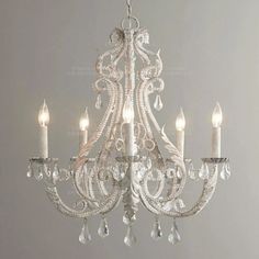 a white chandelier hanging from the ceiling with crystal drops and candles on it