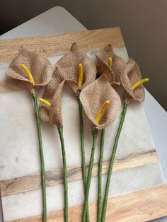 three flowers are on a cutting board with burlap and twine around them