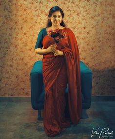 a woman in a red sari holding flowers