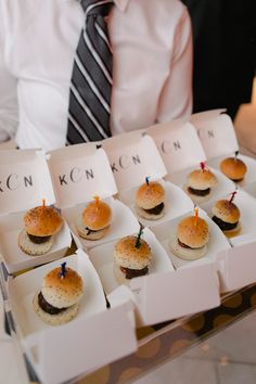 a man in a tie is holding a tray with small sandwiches on it and candles