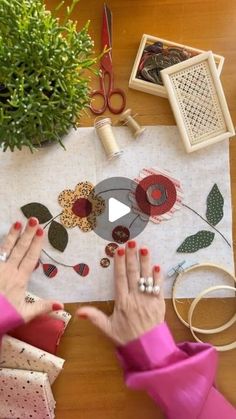 a woman is working on an art project with her hands and sewing supplies around the table