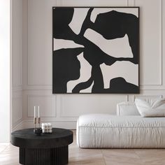 a black and white painting hanging on the wall next to a couch in a living room