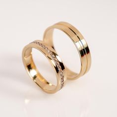 two gold wedding rings with white diamonds on each one, set against a white background