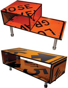 an orange and black sign sitting on top of a wooden table next to another sign