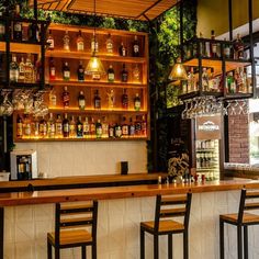 the bar has many bottles and glasses on it, along with two stools at the bar