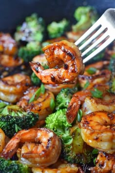 broccoli and shrimp being cooked in a skillet with a fork on top