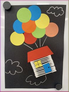 a paper house with balloons floating in the air on a black background, cut out from construction paper