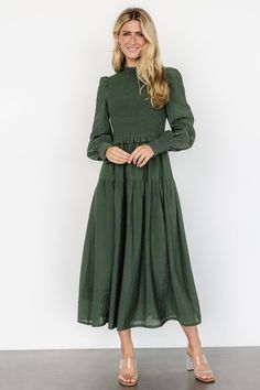 The Daria Smocked Maxi Dress in Juniper Green is a darling choice for any occasion, featuring a shirred mock neckline, smocked bodice, and puffed sleeves with shirred cuffs. This fully lined dress includes a delicate ruffle at the waist, a single tier at the top of the skirt, and unlined sleeves for a touch of elegance. Winter Dresses Casual, Modest Dresses For Church, Sunday Best Dress, Holy Girl, Juniper Green, Smocked Maxi Dress, Dresses Casual Winter, Long Sleeve Dresses, Darling Dress