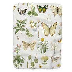 a white blanket with butterflies and flowers on the front, along with green leaves in the back