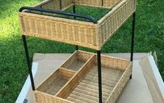 two wicker baskets sitting on top of a cardboard box in front of some grass