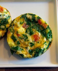 two muffins with spinach and cheese on a white plate