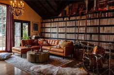 a living room filled with lots of furniture and bookshelves next to a window