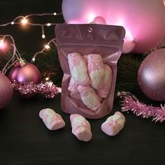 pink and white marshmallows are in a bag next to christmas ornaments