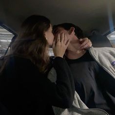 a man and woman kissing in the back of a car