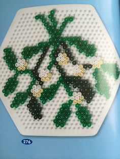 a white hexagonal object with green and yellow beads