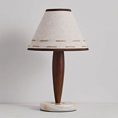 a lamp that is on top of a white table with a wooden base and fabric shade