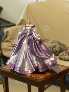 a purple and white dress sitting on top of a wooden table next to a chair