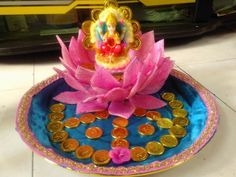 a small buddha statue sitting on top of a blue plate filled with coins and flowers