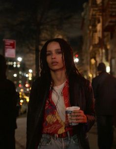 a woman with dreadlocks is walking down the street holding a drink in her hand