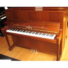 an upright piano sitting on top of a hard wood floor