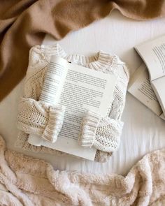 an open book on top of a bed next to some blankets