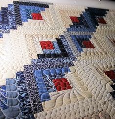 a close up of a quilt on a bed with red, white and blue designs