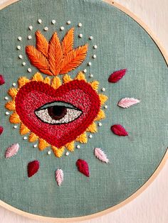 an embroidered heart with eye surrounded by leaves