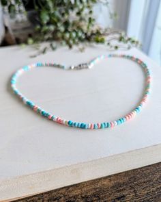 a beaded necklace is sitting on a table next to a potted plant in the background