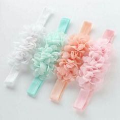 three baby headbands with flowers on them, one in pastel colors and the other in light pink