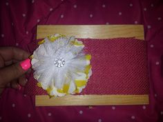 a person is holding a piece of fabric with a flower on it and a pin in the middle