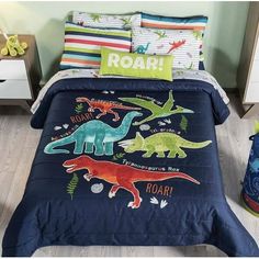 a child's bed with blue and green dinosaur bedspread, pillowcases and pillows