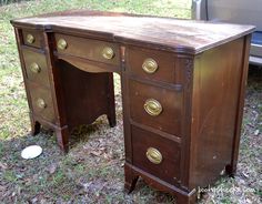 an old wooden desk with brass knobs in the grass next to a parked car