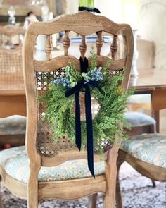 a chair with a wreath on the back of it sitting in front of a dining room table