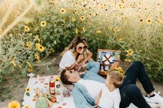 a family picnicking in the sunflowers with an easel and some drinks