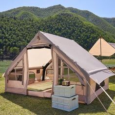 a tent is set up in the grass with two umbrellas and a bed inside